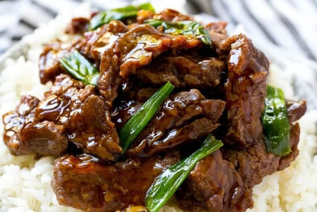 Close-up of slow cooker Mongolian beef with rice in a bowl.