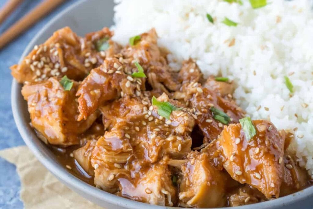 Slow cooker sesame chicken with rice in a bowl.