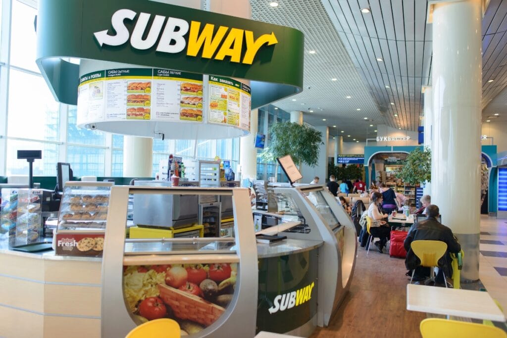 Interior of a Subway restaurant with counter and menu boards visible..