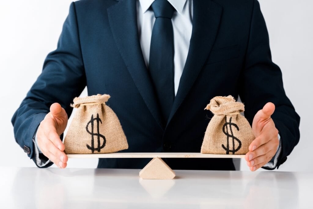 Businessman holding scales with money bags.