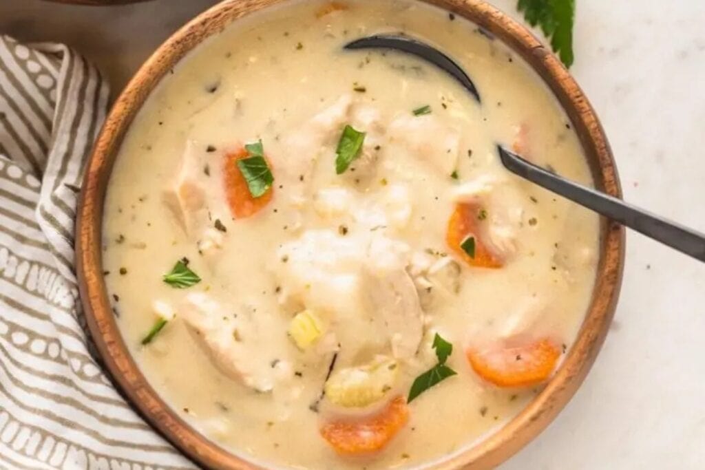Turkey and dumplings soup served in a wooden bowl.