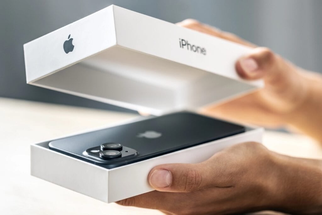 Man opening an iPhone box with a new phone inside.