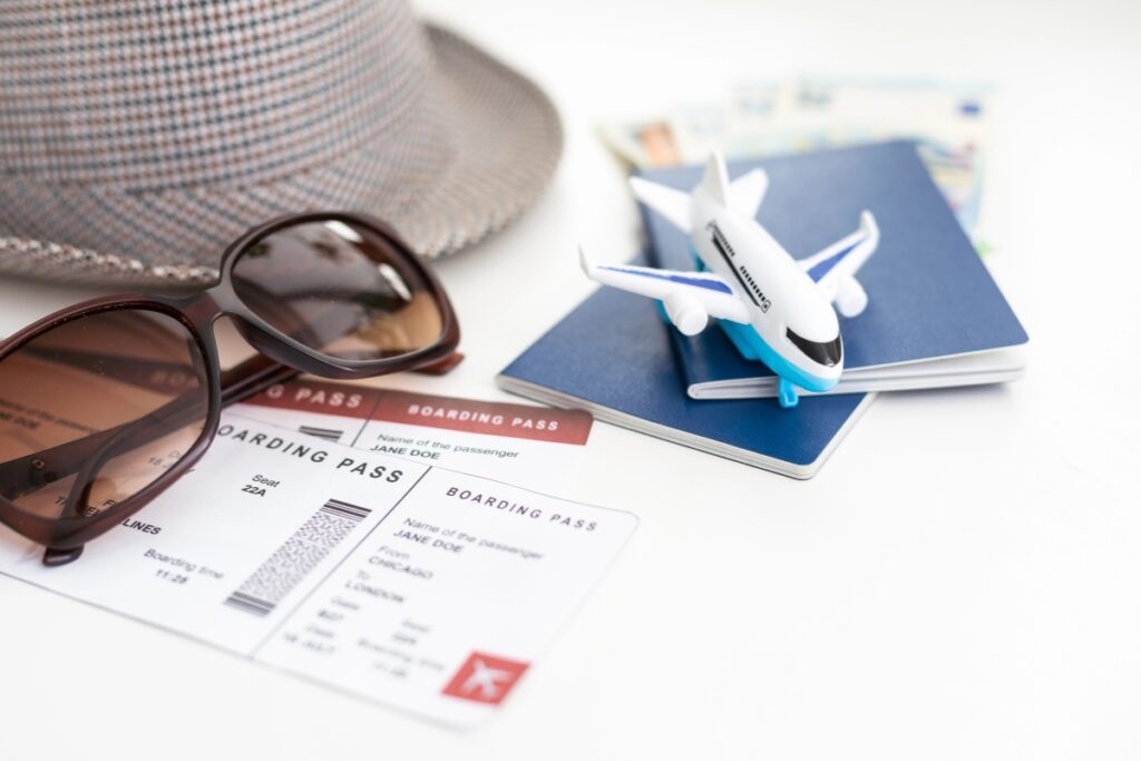 Travel items with boarding passes, passport, toy plane, and sunglasses.