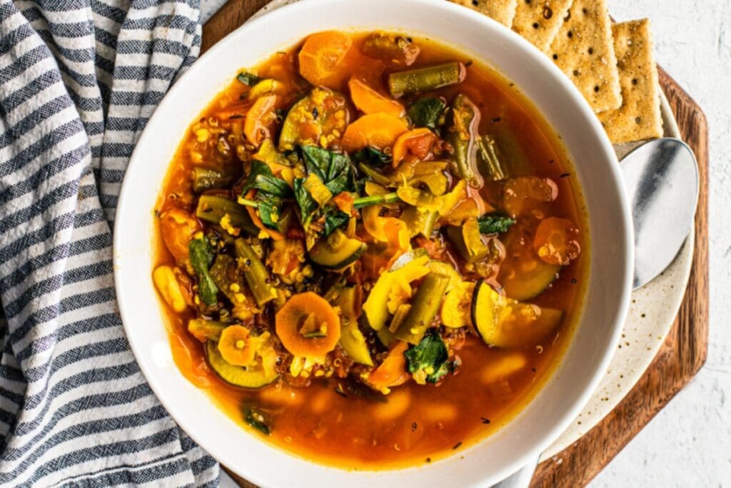 Vegetable and quinoa soup in a white bowl.