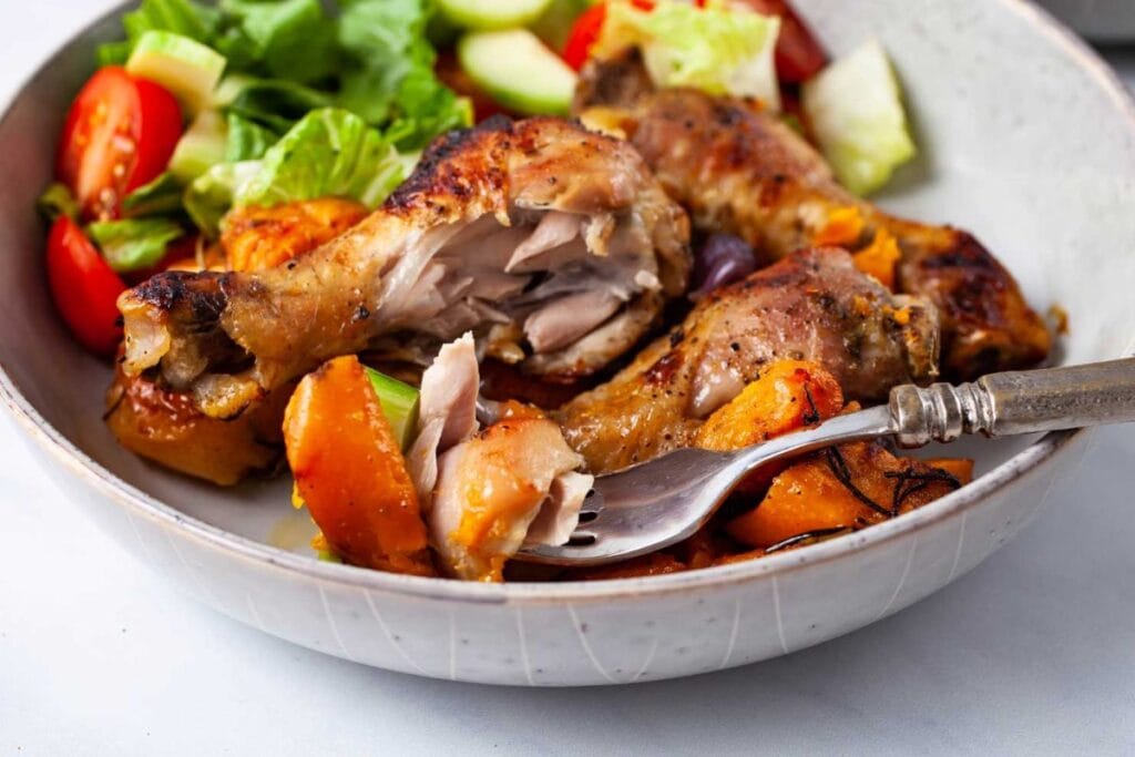 Baked chicken drumsticks with sweet potatoes and a side salad.