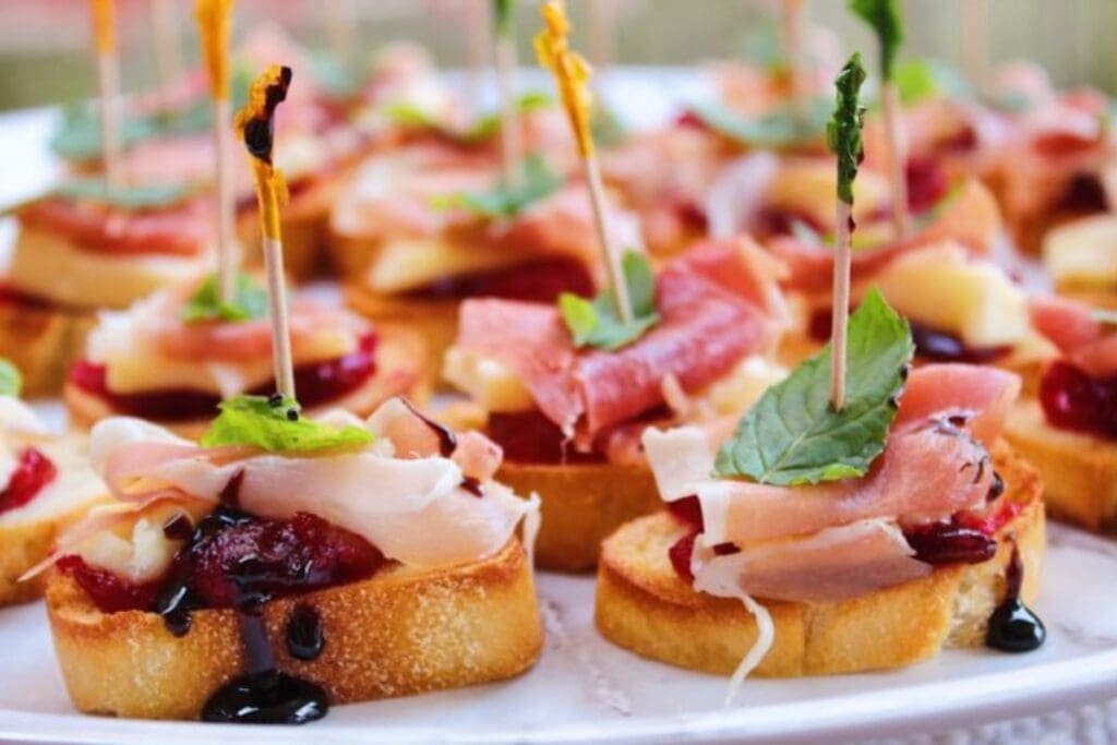 Close-up of crostini appetizers with brie, prosciutto, and balsamic glaze.