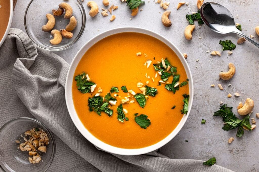 Overhead view of carrot ginger soup with cilantro and cashews.