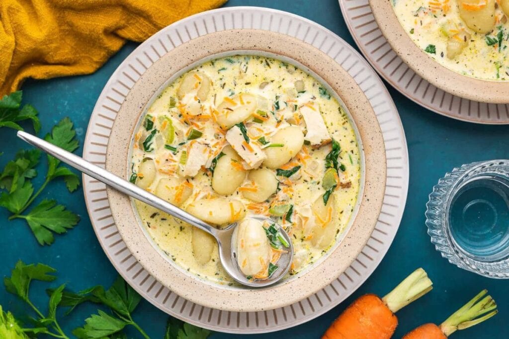 Overhead shot of chicken gnocchi soup with spinach and carrots in a bowl.
