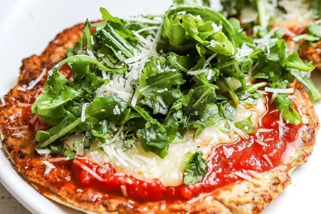 Pizza with tomato sauce, cheese, arugula, and parmesan.