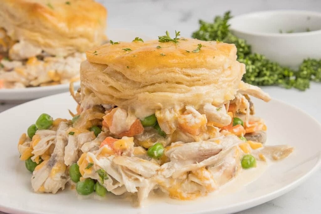 Chicken pot pie casserole with biscuit topping on a white plate.