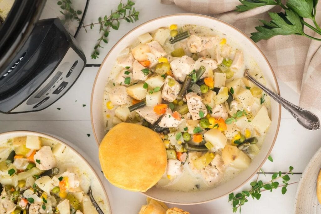 Overhead shot of chicken pot pie soup with a biscuit on the side.