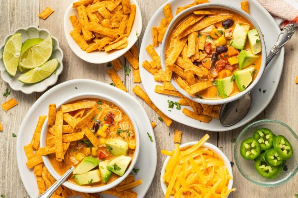 Bowls of chicken tortilla soup with avocado, tortilla strips, and cheese.