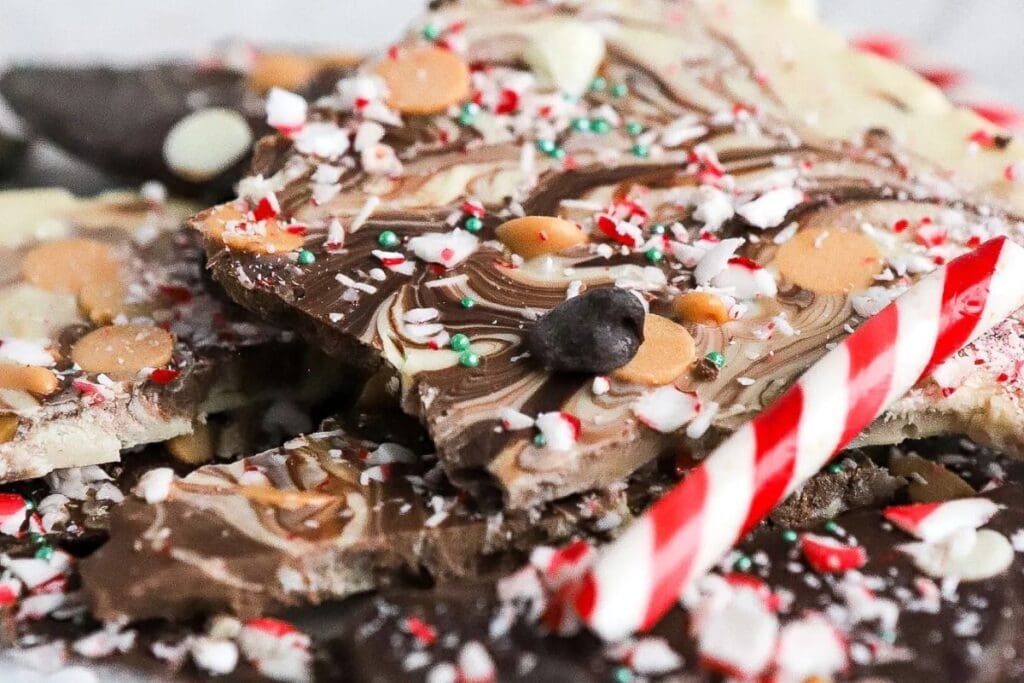 Close-up of Christmas bark with swirls, sprinkles, and a candy cane.