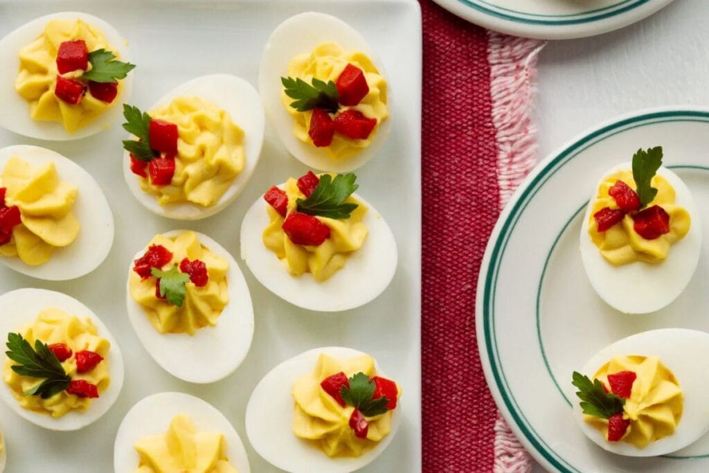 Overhead shot of deviled eggs garnished with red pepper and parsley.