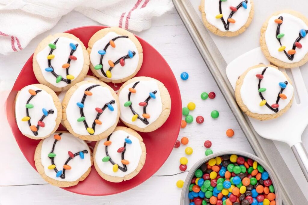Christmas light cookies with white frosting, black lines, and candy lights on a red plate.