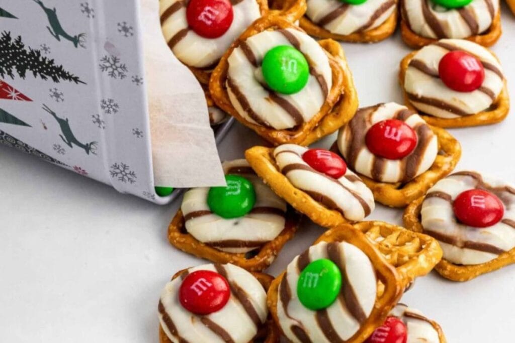 Pretzel hugs with M\&Ms spilling from a Christmas tin.