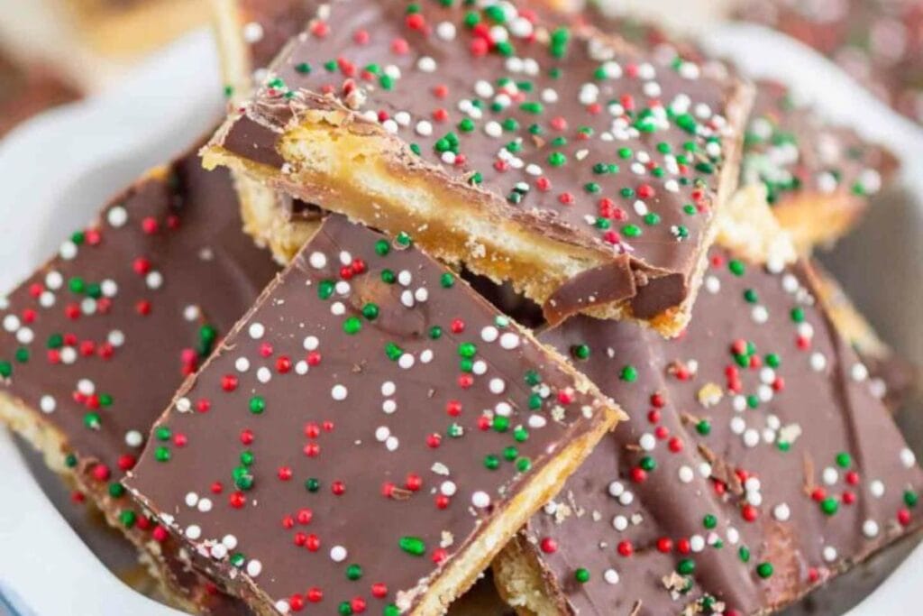 Stacked Christmas Ritz cracker toffee with sprinkles on top.
