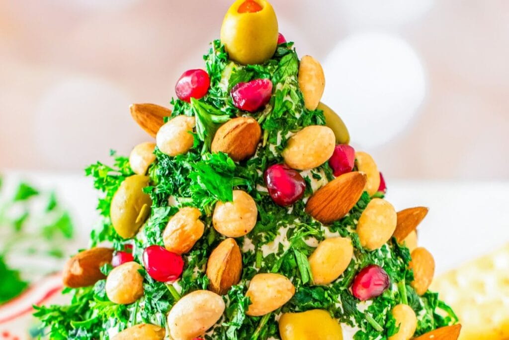 Close-up of a Christmas tree cheese ball with herbs, nuts, and pomegranate seeds.