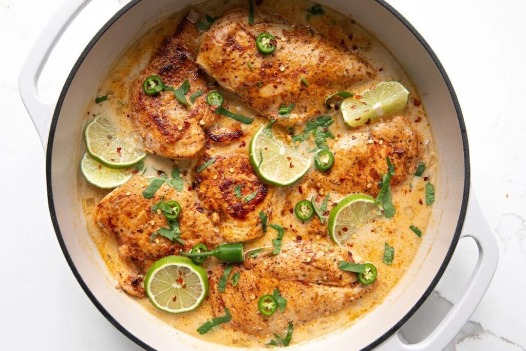 Chicken breasts in a creamy sauce with lime slices and jalapeño peppers.