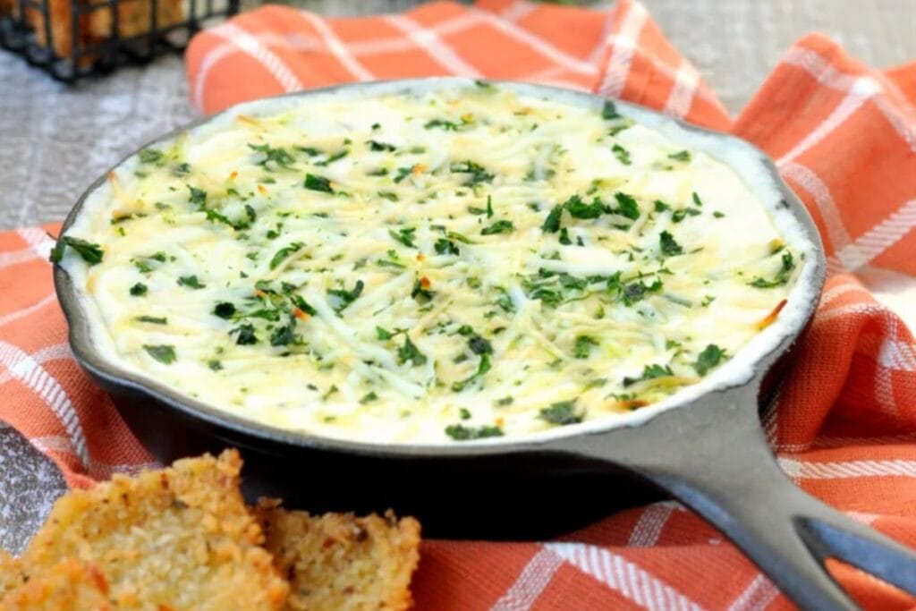 Crab Alfredo Lasagna Dip in a cast iron skillet with garlic bread.