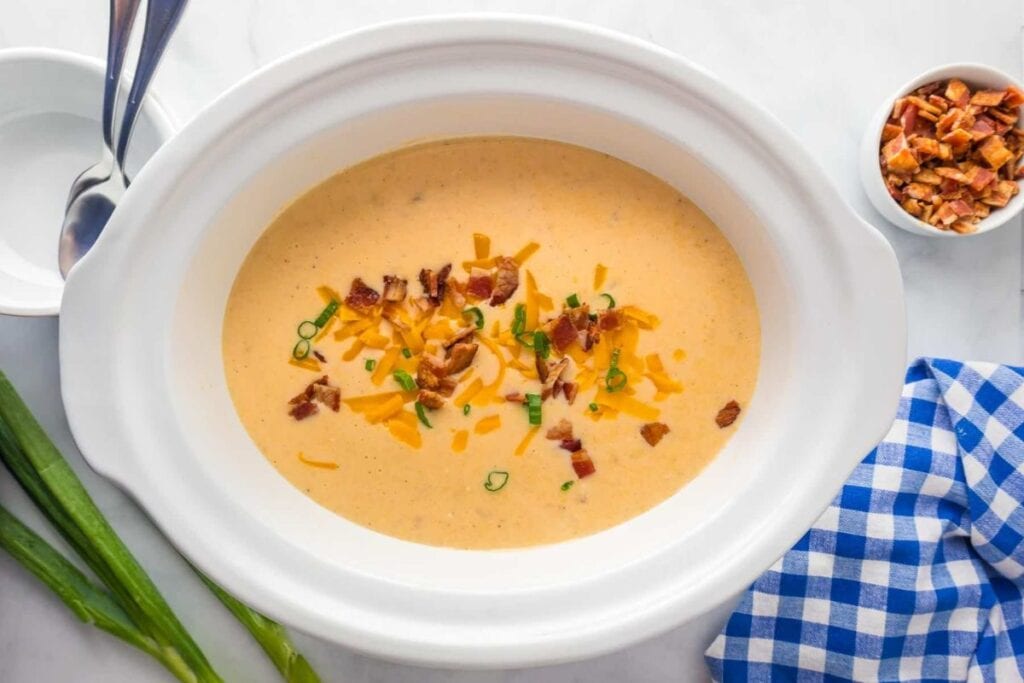 Overhead shot of potato soup in a white bowl topped with bacon and cheese.