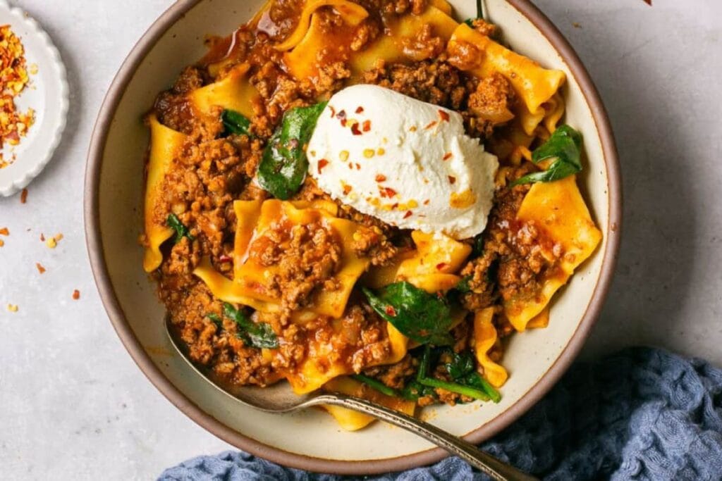 Bowl of lasagna soup with ricotta cheese and spinach.