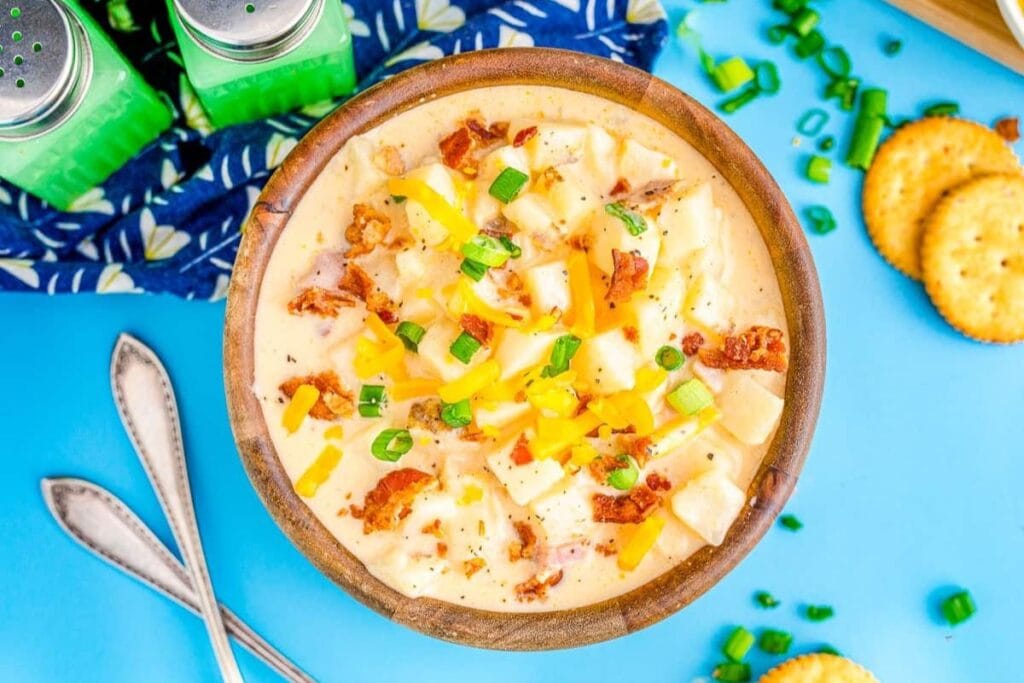 Overhead shot of potato soup in a wooden bowl, garnished with bacon and chives.