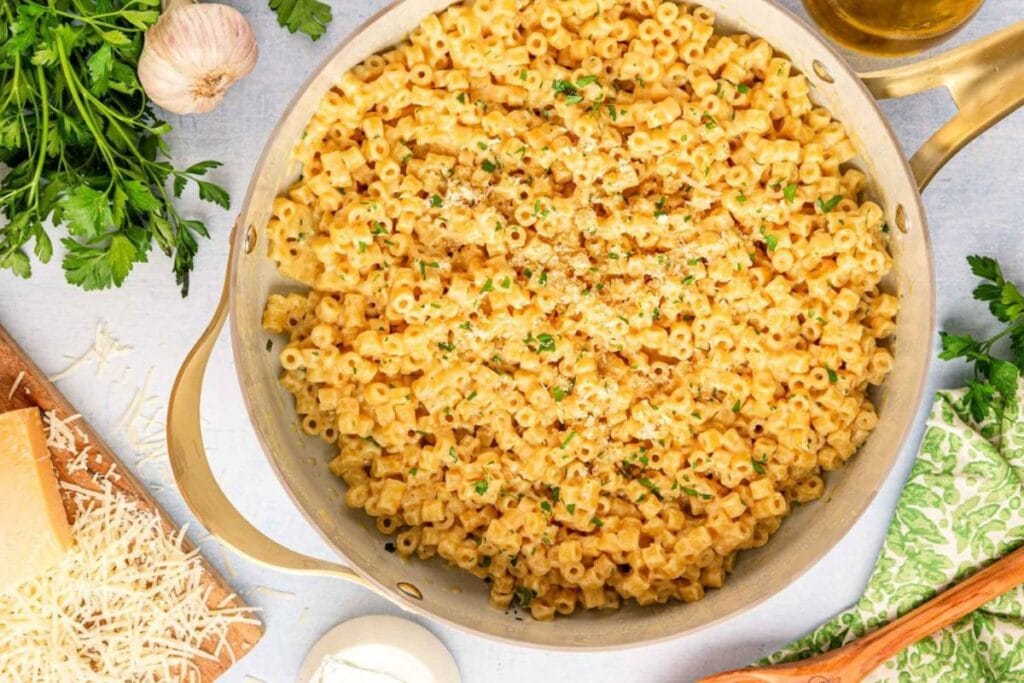 Overhead shot of creamy ditalini pasta with cheese and parsley in a skillet.