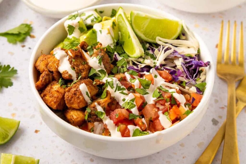 Fish taco bowl with rice, cabbage, avocado, pico de gallo, and lime.