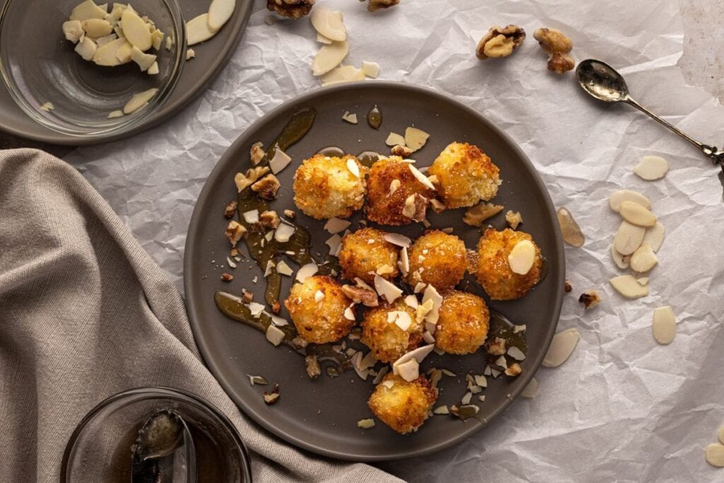 Fried goat cheese balls with honey and almonds on a gray plate.