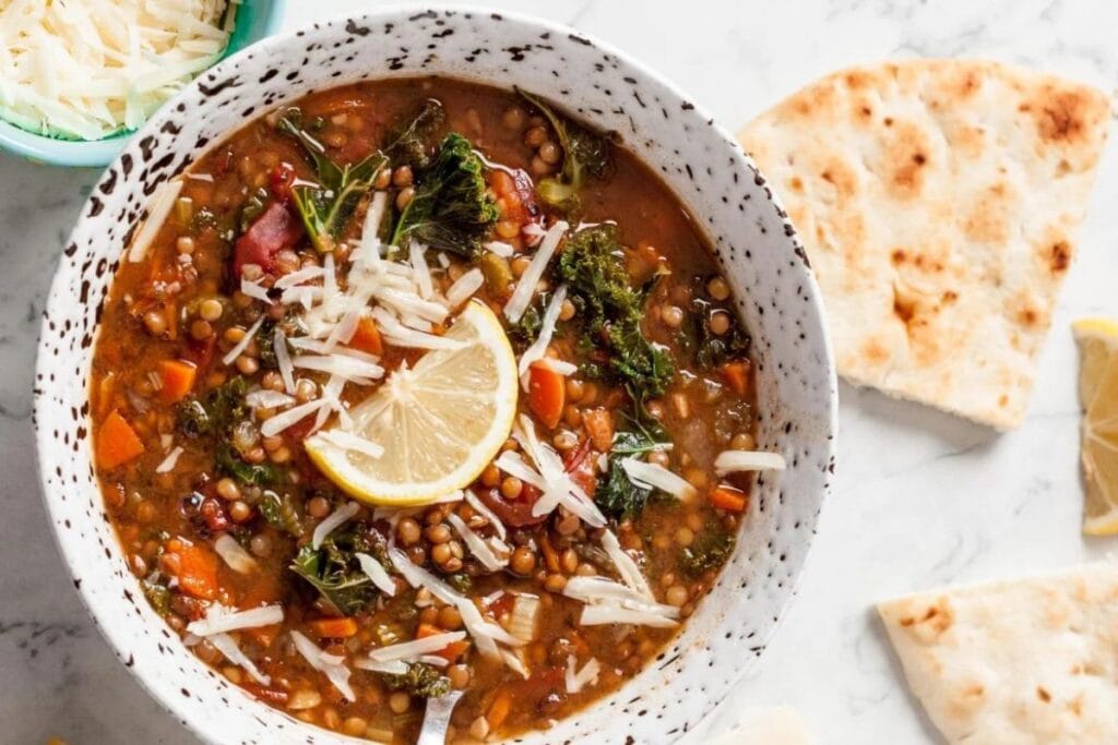 Overhead shot of lentil soup with kale, lemon, and parmesan cheese in a bowl.