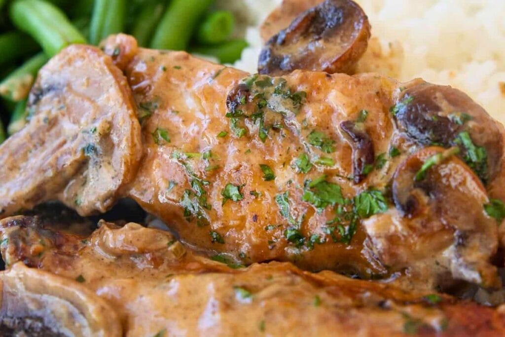 Chicken breast with mushroom sauce, served with rice and green beans.