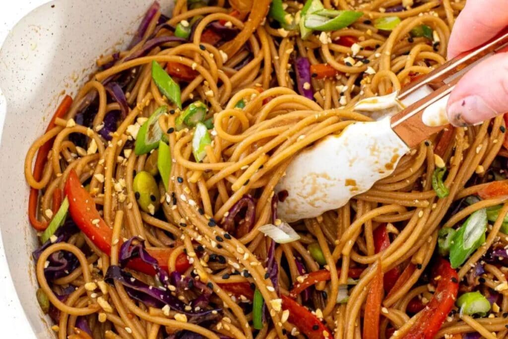 Stir-fried noodles with red cabbage, bell peppers, and green onions.