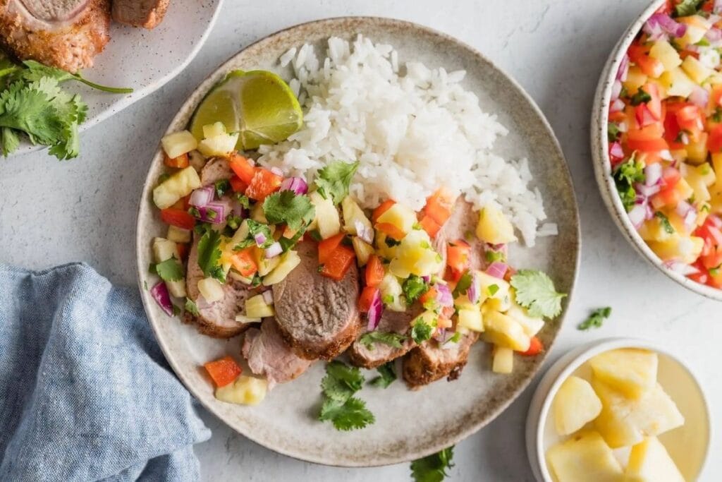 A close up shot of pork tenderloin with pineapple salsa.