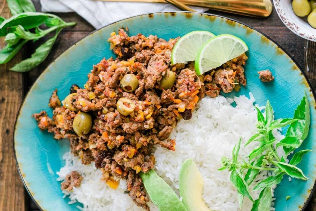 Ground beef picadillo with rice, olives, avocado, lime, and basil.