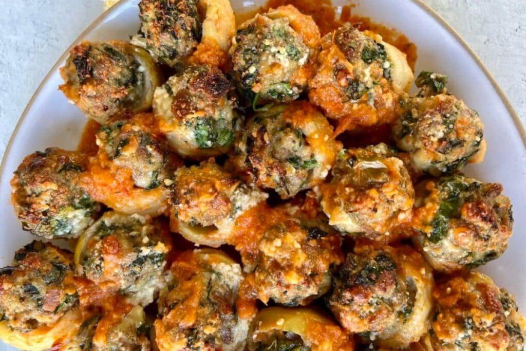 Stuffed pasta shells with spinach and cheese in red sauce on a plate.