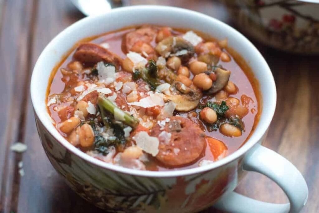 A close up shot of sausage and bean kale stew.
