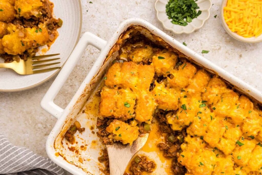 Tater tot casserole with beef and cheese in a white baking dish.