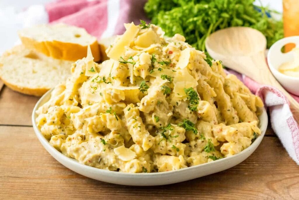 Creamy pasta dish with chicken, garnished with parsley and parmesan cheese. Bread on the side.