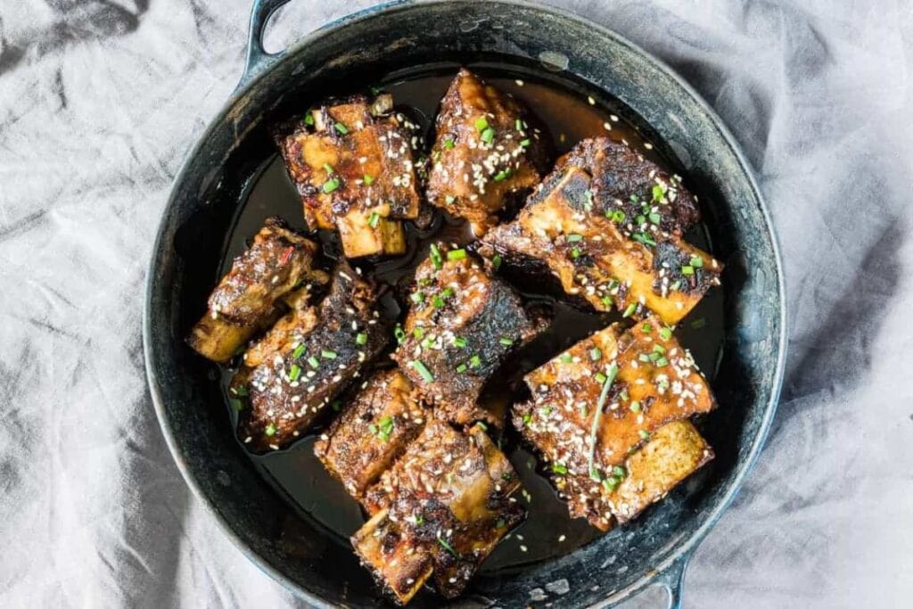 Overhead shot of slow cooker short ribs with sesame seeds and chives.
