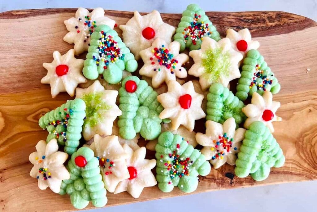 Christmas spritz cookies, some tree-shaped with sprinkles, some star-shaped with red candy.