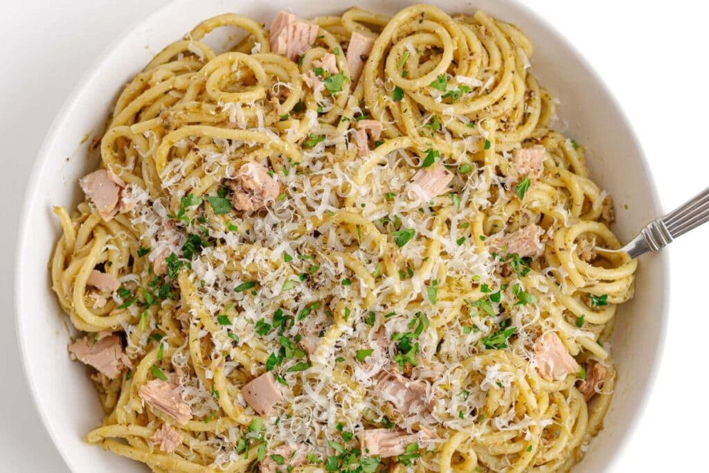 Tuna pasta in a white bowl, topped with parmesan and parsley.