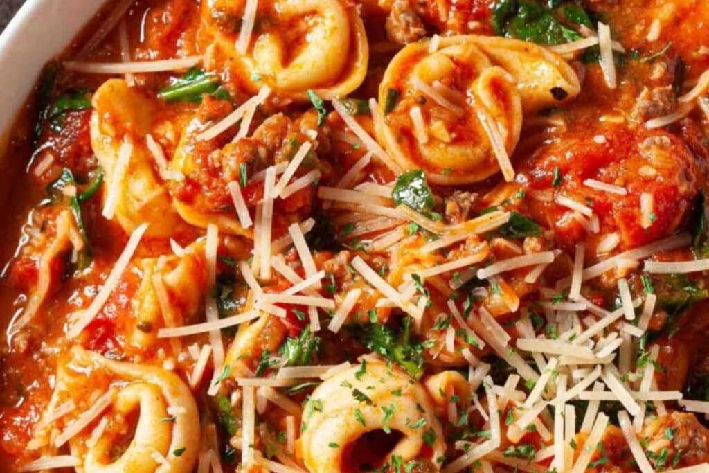 Tortellini, sausage, and spinach in a tomato sauce, topped with shredded Parmesan cheese.