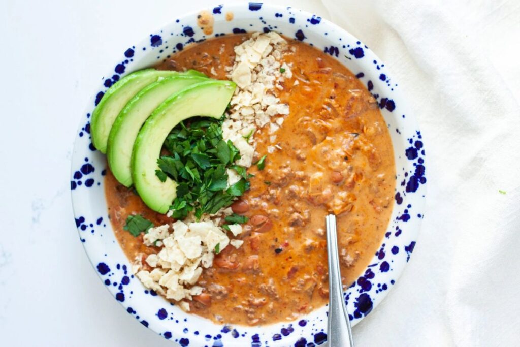 Bowl of creamy venison soup topped with avocado, cilantro, and tortilla chips.