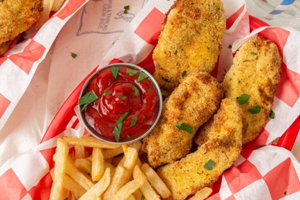 Chicken tenders with fries and ketchup on a tray.
