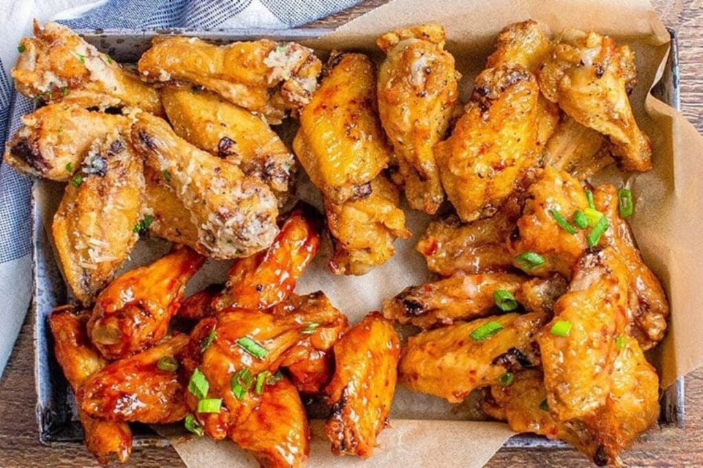 Air fryer chicken wings in four different flavors on a tray.