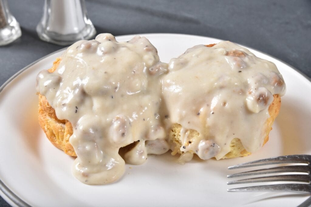 Biscuits topped with creamy sausage gravy on a plate.