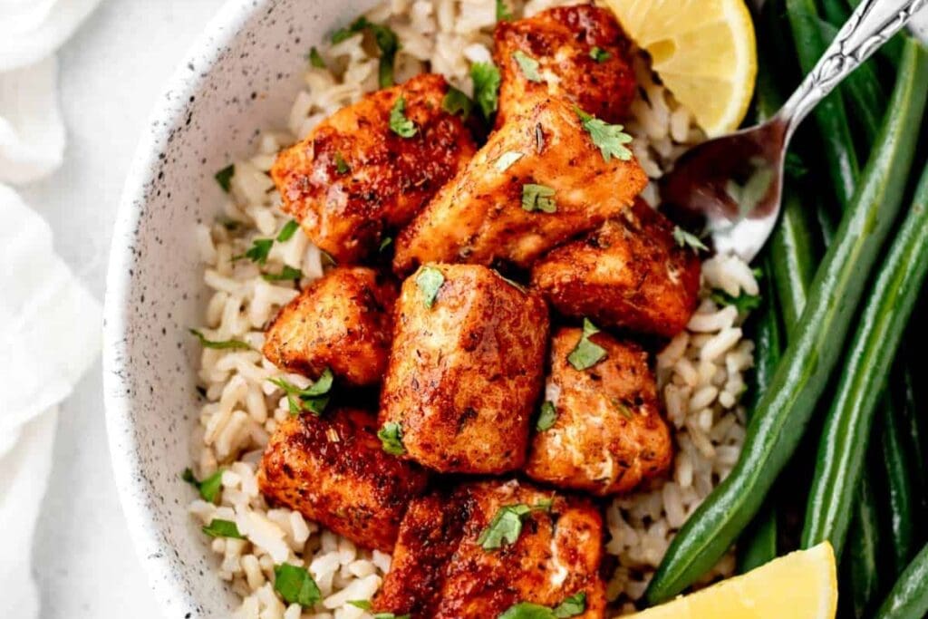 Close-up of blackened salmon bites on a plate with green beans.