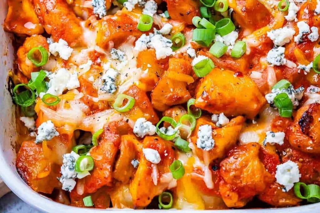 Buffalo chicken casserole in a baking dish topped with melted cheese and green onions.