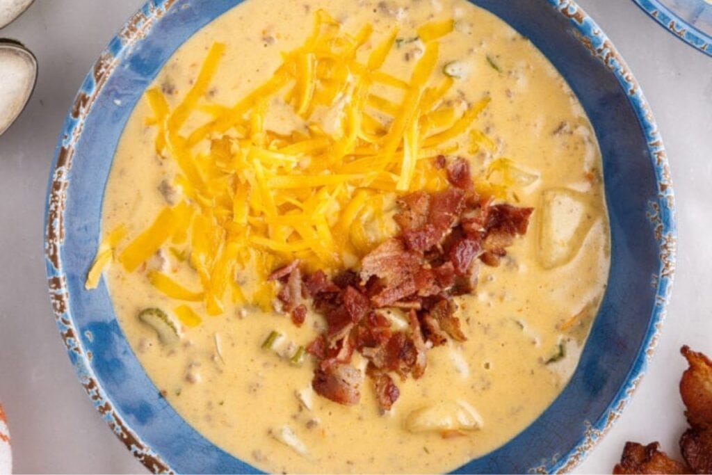 Cheeseburger soup in a bowl topped with bacon and extra cheese.